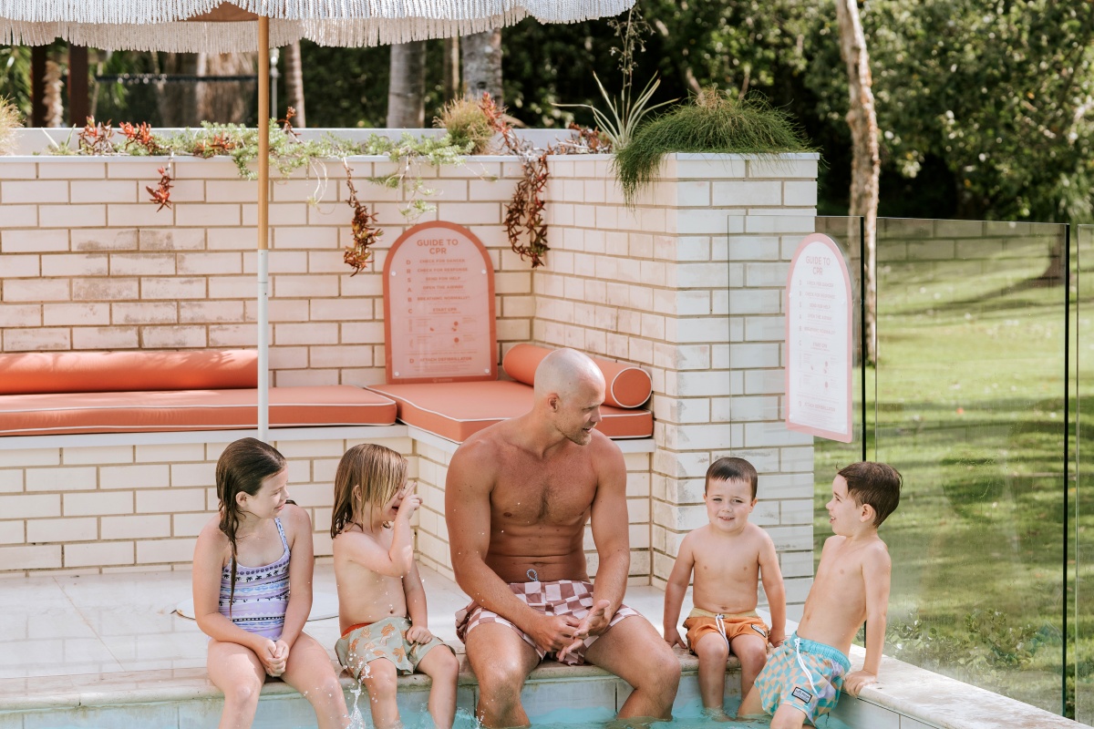 Jett Kenny with kids in pool displaying pink pool safety sign